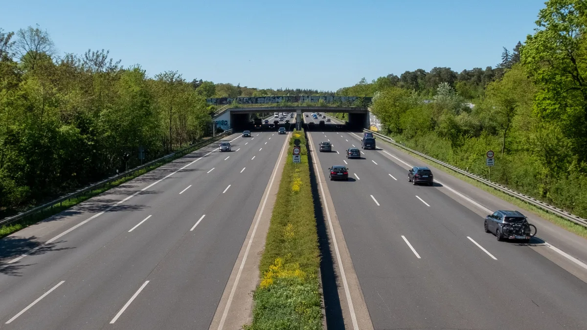 Freier Blick auf den Autobahnverkehr, umgeben von Grün und blauem Himmel.