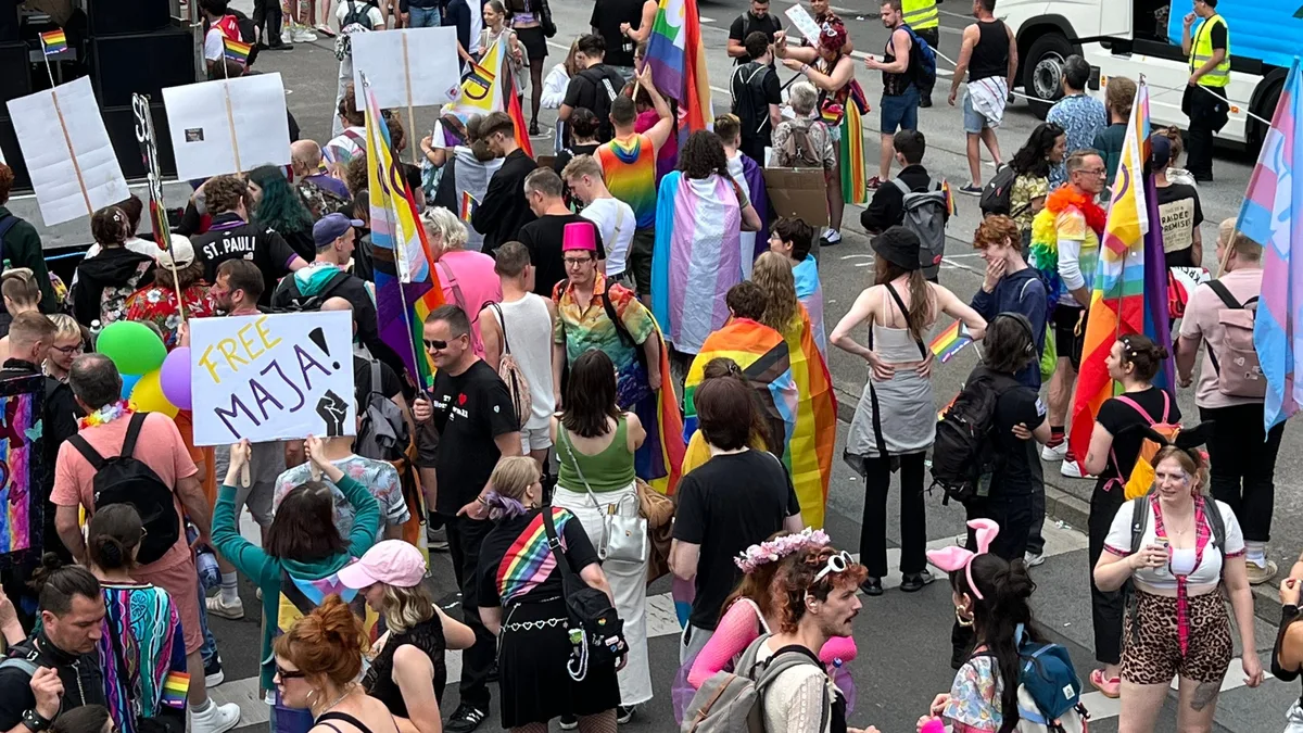 Bunte Menschenmenge feiert Berlin Pride mit Fahnen und Schildern.