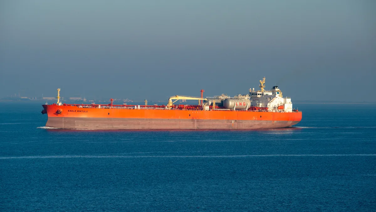 Ein leuchtend orangefarbenes LNG-Tankschiff kreuzt an einem klaren Tag durch ruhige See.