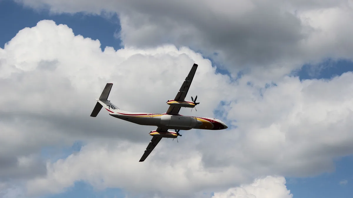 Ein Flugzeug führt während einer Flugshow in La Ferté-Alais, Frankreich, ein akrobatisches Manöver vor einer Kulisse aus Wolken und blauem Himmel durch.
