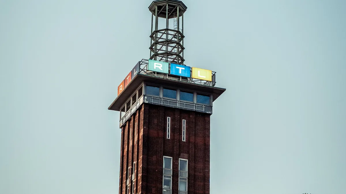 Ikonischer Messeturm in Köln, Deutschland, aufgenommen unter einem klaren blauen Himmel mit Baumästen.