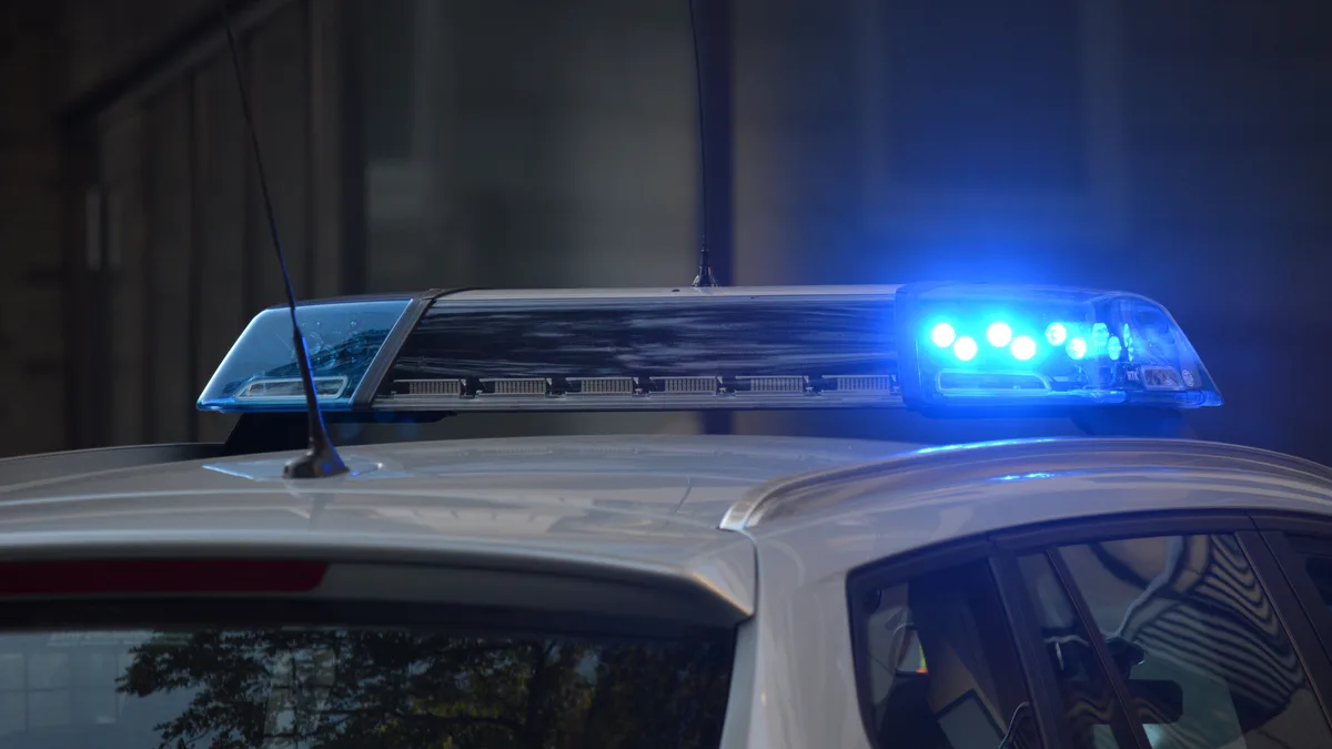 Nahaufnahme der blinkenden blauen Lichter eines Polizeiwagens in einer städtischen Umgebung.