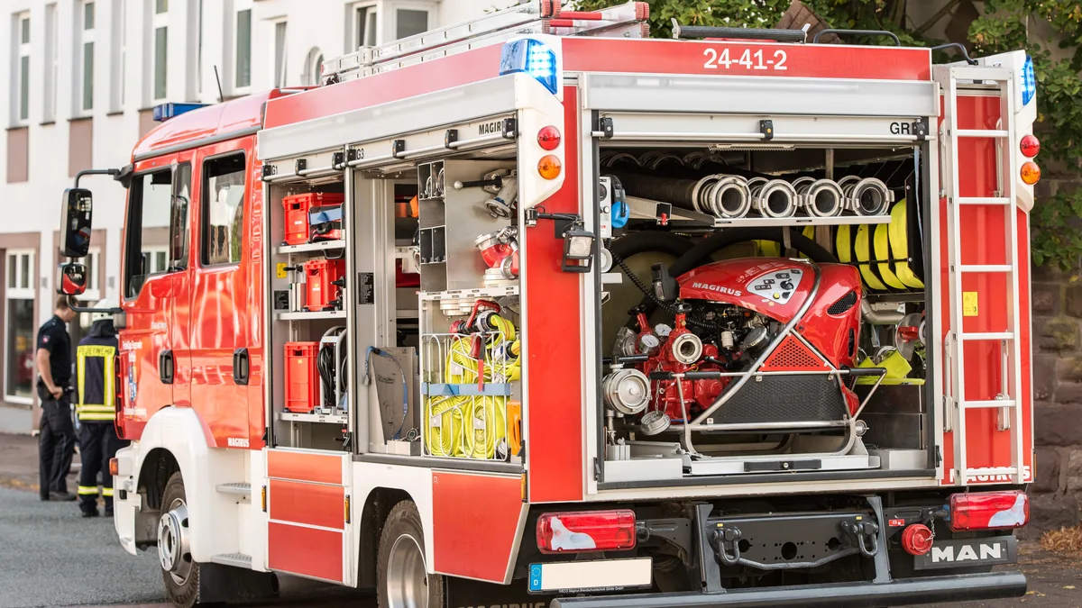 Ein leuchtend rotes Feuerwehrfahrzeug, das auf einer Stadtstraße parkt, mit sichtbarem Equipment und zeigt die Bereitschaft für städtische Notfälle.