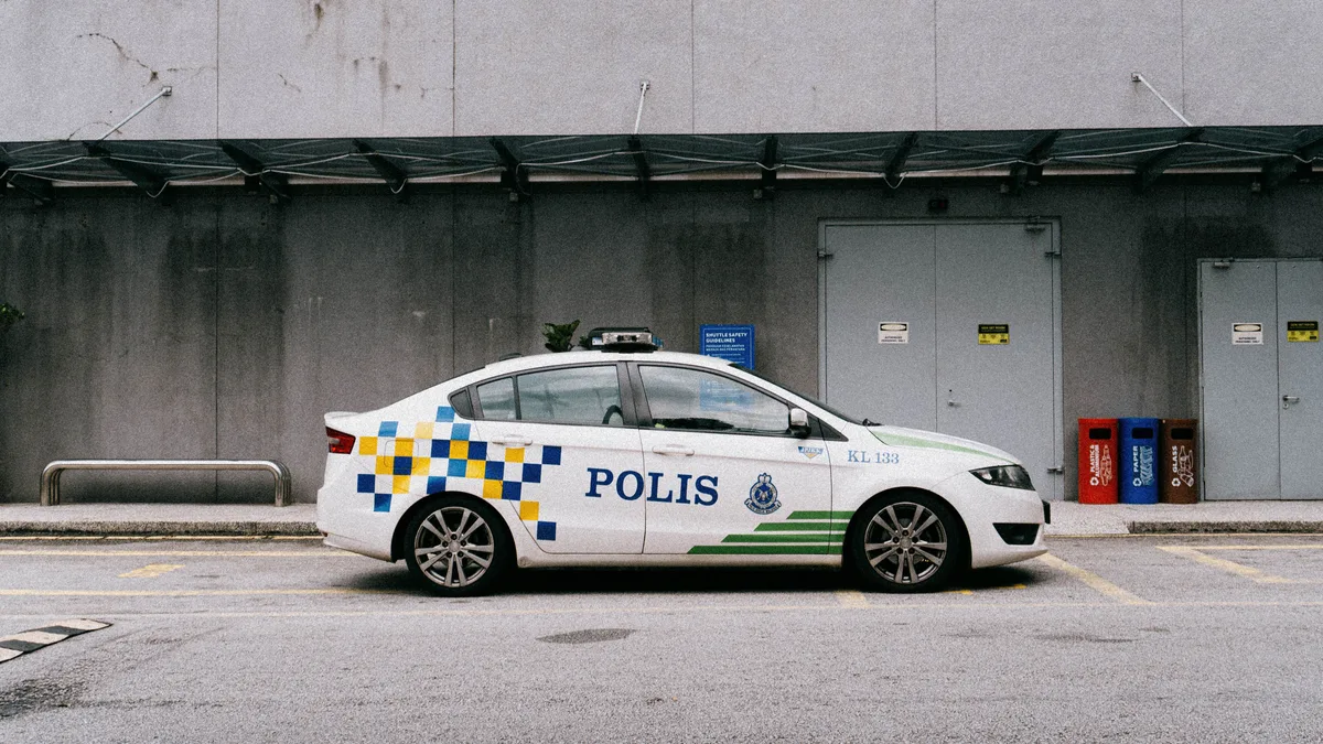 Ein malaysisches Polizeiauto, das in einer städtischen Umgebung geparkt ist und die lokale Strafverfolgung zeigt.