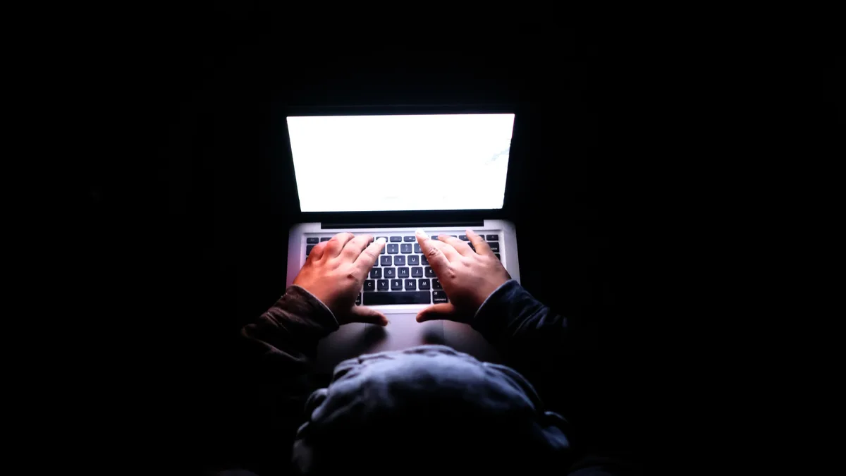 Eine Person in einem dunklen Raum, die auf einem Laptop tippt, was Privatsphäre, Cybersicherheit und Technologie symbolisiert.