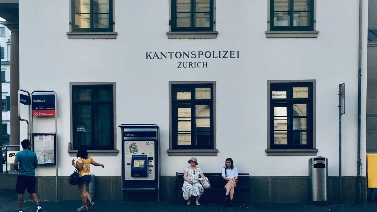 Menschen gehen an der historischen Polizeistation Zürich vorbei und fangen das urbanische Leben ein.