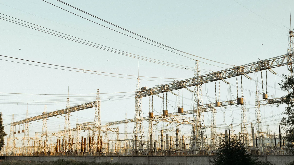 Eine weite Ansicht eines industriellen elektrischen Umspannwerks mit Freileitungen und Türmen im Freien.