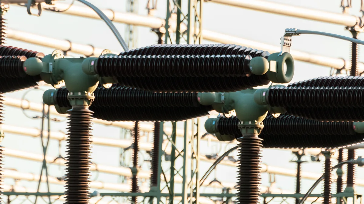 Nahaufnahme von elektrischen Energieanlagen im Freien mit Isolatoren und Leitern.