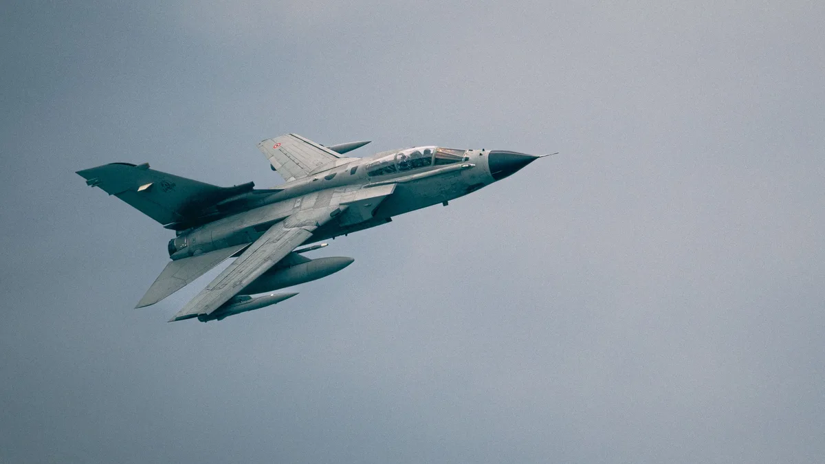 Ein Panavia Tornado-Kampfflugzeug, das durch einen bewölkten Himmel fliegt und Kraft und Geschwindigkeit zeigt.