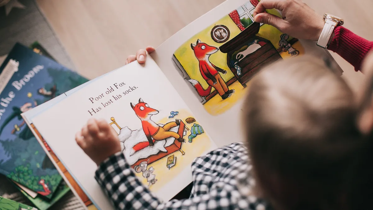 Ein Kind und ein Erwachsener lesen gemeinsam ein illustriertes Kinderbuch in einer gemütlichen Umgebung.