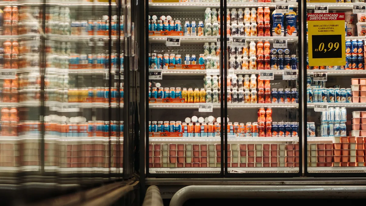 Ein gut beleuchteter Supermarktgang, der eine Vielzahl von Joghurtprodukten in einer gekühlten Auslage zeigt.