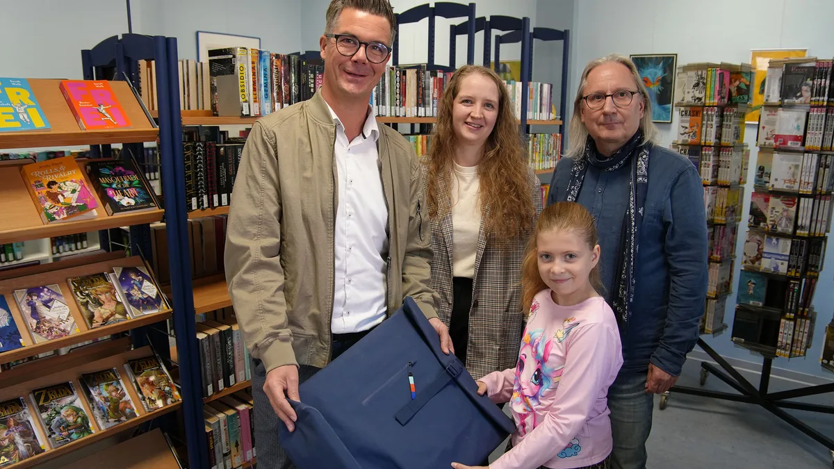 Luna Kahlenbach nimmt in der Stadtbibliothek Neuwied ihren Preis von Bürgermeister Peter Jung entgegen, daneben die Bibliotheksleitung