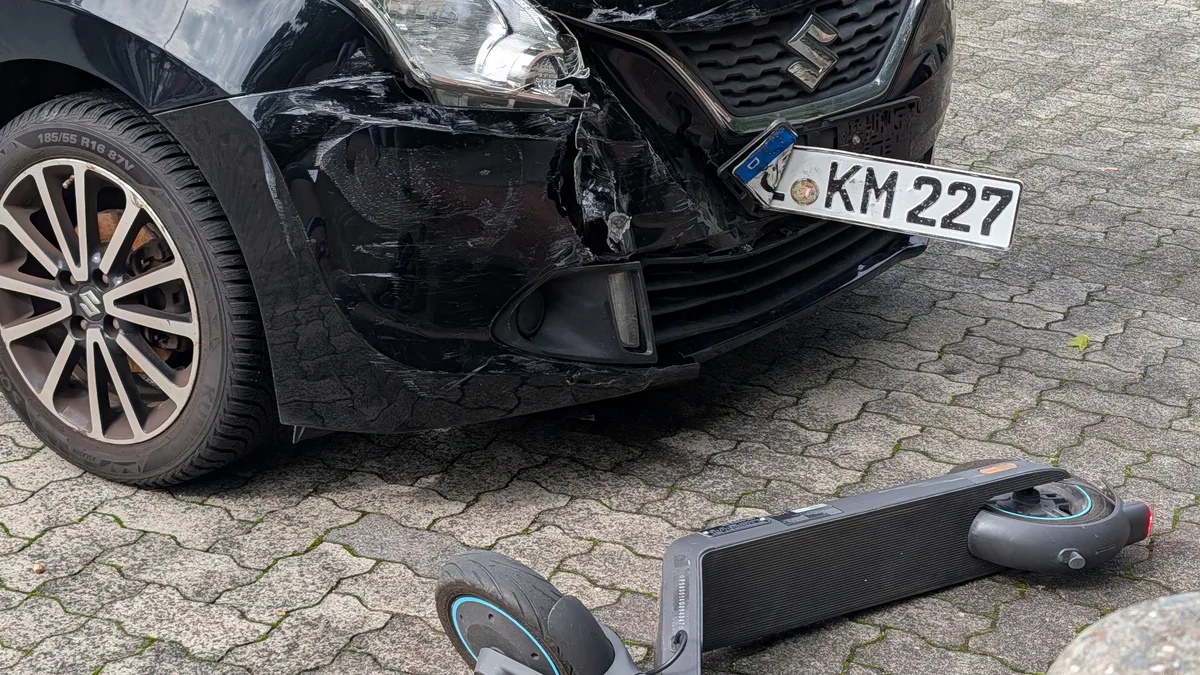 Ein beschädigtes Auto und ein beschädigter Roller nach einer Kollision im städtischen Bereich.