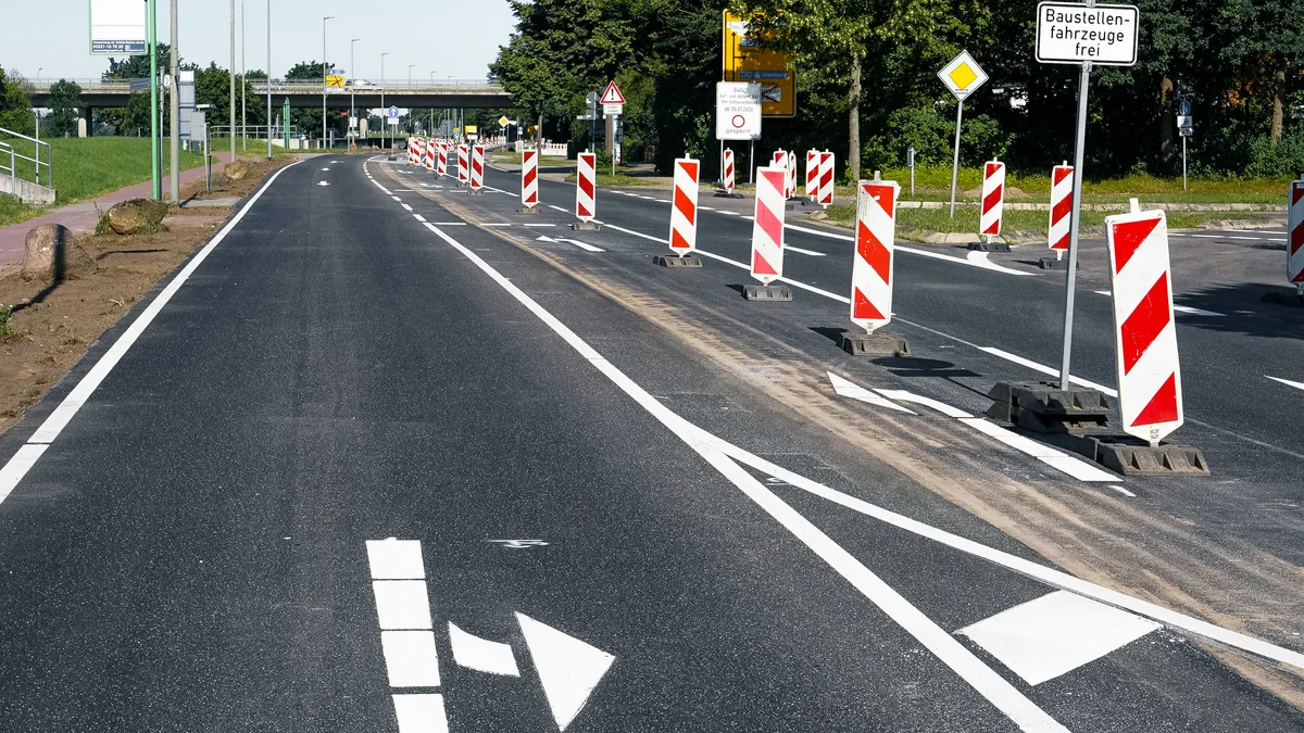 Im Bau befindliche asphaltierte Straße mit Sicherheitsschildern in Geesthacht, Deutschland.