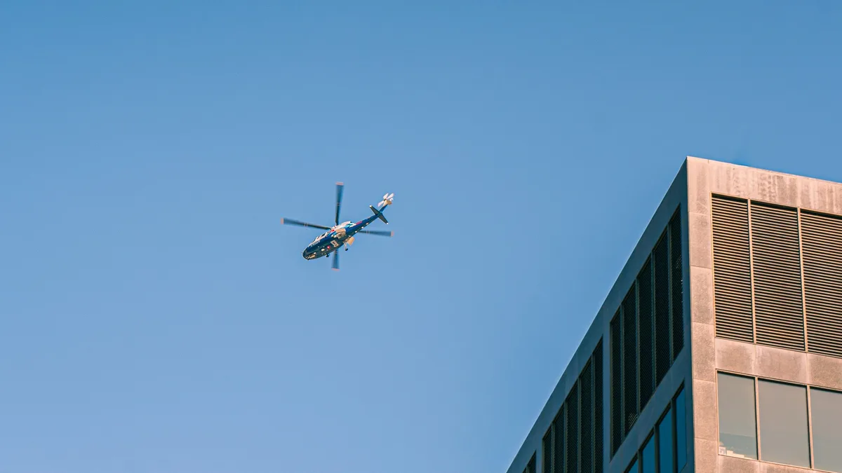 Ein Hubschrauber fliegt vor einem klaren blauen Himmel über die Innenstadt von Grand Rapids und fängt die urbane Architektur ein.