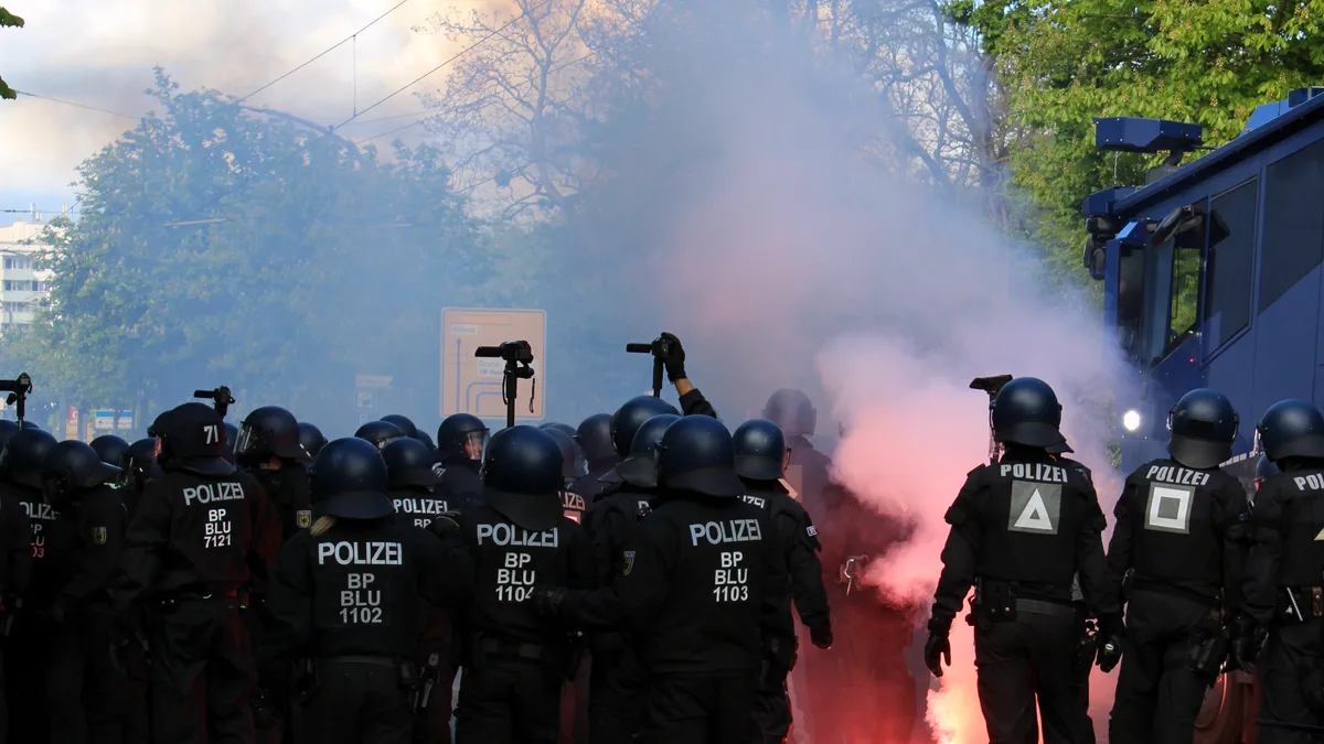 Polizisten in Schutzkleidung bewältigen einen Protest mit Rauchfackeln in Dresden, Deutschland.