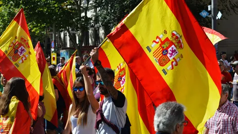 Lebhafte Straßenkundgebung in Barcelona mit Menschen, die spanische Flaggen schwenken und eine lebendige Außenatmosphäre einfangen.