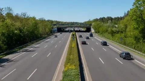 Freier Blick auf den Autobahnverkehr, umgeben von Grün und blauem Himmel.