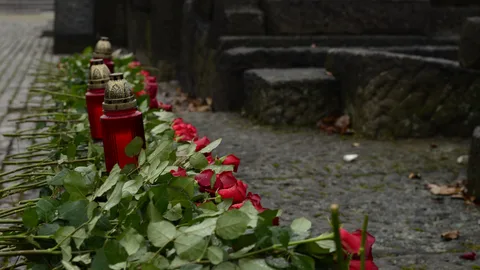 Rote Gedenkkerzen und Rosen wurden im Freien auf Steinstufen zum Gedenken niedergelegt.