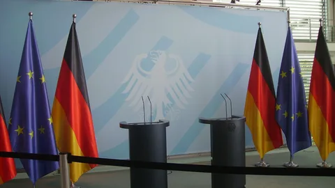 Leere Podien mit deutschen und EU-Flaggen in der Bundeskanzlei, Berlin.