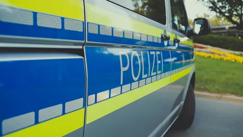 Nahaufnahme eines deutschen Polizeiautos mit dem Aufdruck 'Polizei', das an einem sonnigen Tag im Freien geparkt ist.