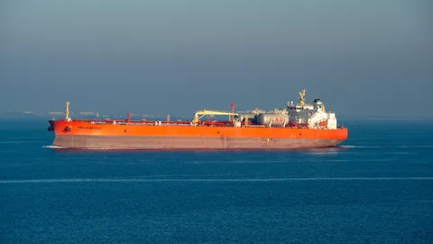 Ein leuchtend orangefarbenes LNG-Tankschiff kreuzt an einem klaren Tag durch ruhige See.