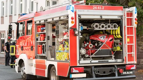 Ein leuchtend rotes Feuerwehrfahrzeug, das auf einer Stadtstraße parkt, mit sichtbarem Equipment und zeigt die Bereitschaft für städtische Notfälle.