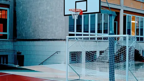 Ein nasser Basketballplatz neben einem Schulgebäude in Verona, Italien, tagsüber.
