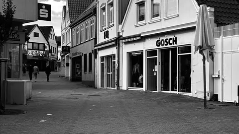 Eine malerische europäische Straße mit Geschäften in Schwarz-Weiß, die ein nostalgisches urbanes Gefühl vermittelt.