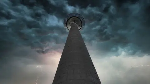 Niedrige Perspektive einer hohen Turm gegen einen dramatischen stürmischen Himmel mit Blitzen.