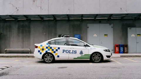 Ein malaysisches Polizeiauto, das in einer städtischen Umgebung geparkt ist und die lokale Strafverfolgung zeigt.