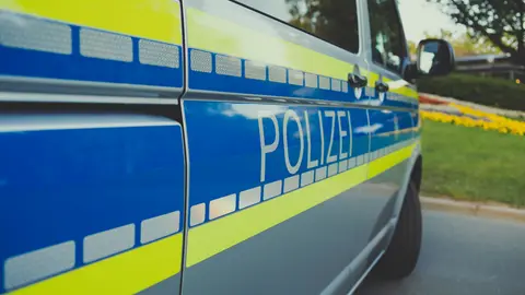 Nahaufnahme eines deutschen Polizeiautos mit dem Aufdruck 'Polizei', das an einem sonnigen Tag im Freien geparkt ist.