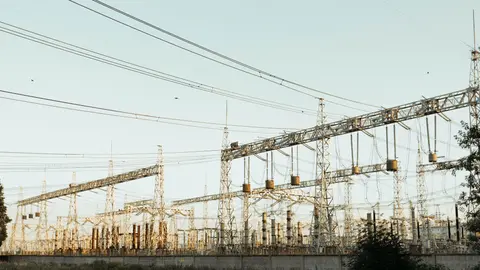 Eine weite Ansicht eines industriellen elektrischen Umspannwerks mit Freileitungen und Türmen im Freien.