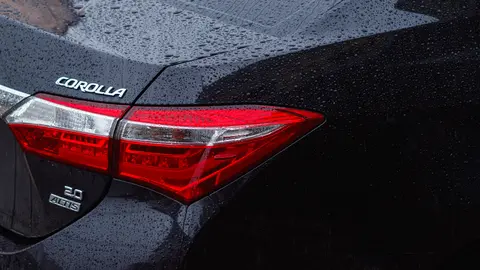 Detaillierte Rückansicht eines Toyota Corolla im Regen, die Wassertropfen auf der Fahrzeugoberfläche zeigt.