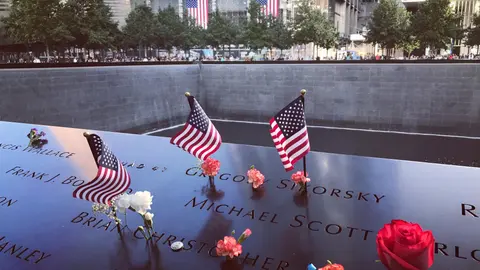 Eine berührende Hommage im 9/11-Memorial in NYC mit Flaggen und Blumen zu Ehren der Opfer.
