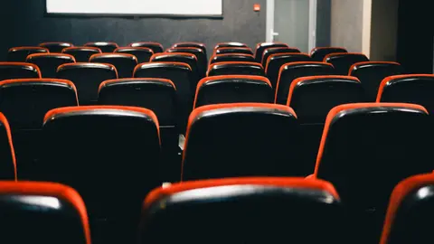 Eine filmreife Ansicht eines leeren Theaters mit rot umrandeten Sitzen, perfekt für Filmthemen.